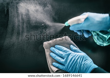 Surface home cleaning spraying antibacterial sanitizing spray bottle disinfecting against COVID-19 spreading wearing medical blue gloves. Sanitize surfaces prevention in hospitals and public spaces. Royalty-Free Stock Photo #1689146641