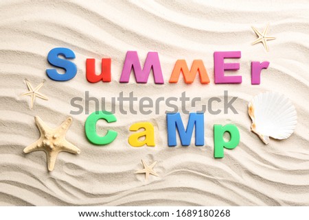 Flat lay composition with phrase SUMMER CAMP made of magnetic letters on sand