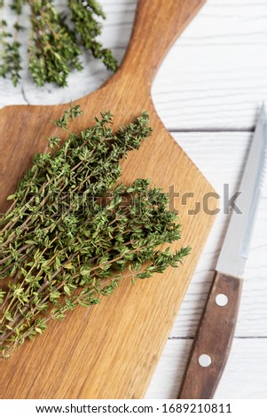 Close up thyme on board at white background with knife. Bunch of thyme on yellow wooden cut board. Concept of kitchen herbs picture
