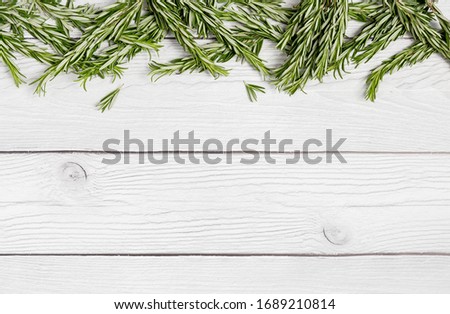 border with rosemary at white wood background. Top view, flat lay, lay out, view from above. Concept of background for text menu or poster. Ingredient for dish. Summer picture