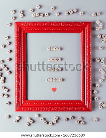 Text STAY HOME SAVE LIVES. The message consists of wooden cubes on a gray background in a red frame.