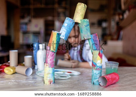 Cute girl coloring toilet paper rolls to use them as if paper blocks to build a tower, home activity during lockdown, do it yourself and zero waste concept Royalty-Free Stock Photo #1689258886