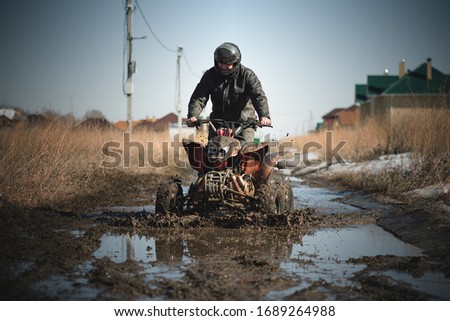 Biker riding quad bike on dirty countryside road.