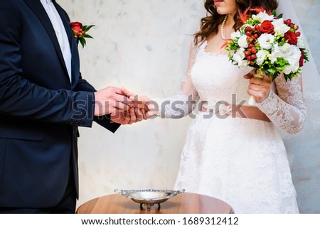 Man putting engagement ring on bride's finger. Just married couple. Wedding rings. Selective focus. Bride with colorful bouquet of roses
