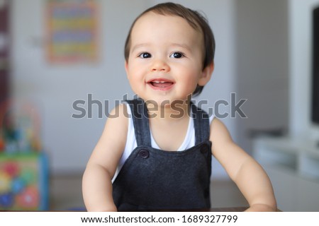 Cute baby boy smiling face saliva on his lips about teething first milk teeth. Mixed race Asian-German infant 9-10 months old playing at home. Healthy child. Royalty-Free Stock Photo #1689327799