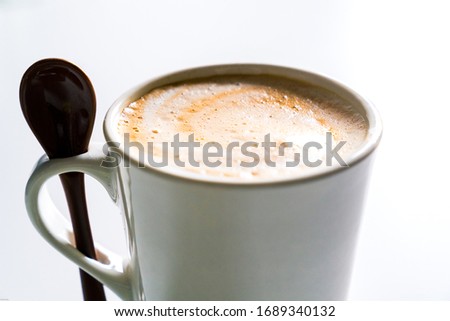 Creamy latte in a white cup with a spoon.