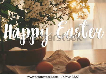 Happy Easter text. Easter greetings lettering. Natural Easter eggs in sunset warm light on linen rustic fabric with cherry blooming flowers  on  wooden table. Greeting card