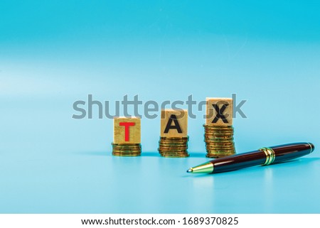 Coin with Wooden blocks text TAX Business and finance concept.