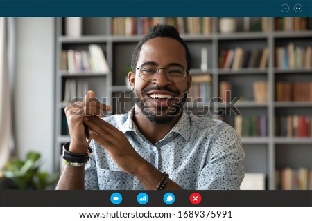 Headshot portrait screen application view of overjoyed young African American man sit at home have pleasant web conference on computer, smiling biracial millennial male talk on video call online Royalty-Free Stock Photo #1689375991