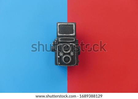 Top view of a vintage toy camera on a two color background which are blue and red.