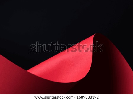 Abstract - a single sheet of rolled red paper on black background. Simple, isolated object with text space perfect for illustrating various concepts and ideas. Selective focus (shallow DOF).