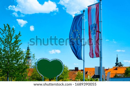 Austrian and EU flags in Austria. Modern european empty green Traffic warning road sign - heart shape safety construction symbol. Street blank information concept. Transportation board frame.