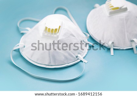 White face medical mask against virus, flu and coronavirus isolated on light blue background Royalty-Free Stock Photo #1689412156
