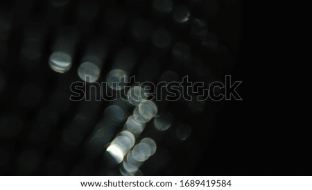 Close up of rotating blurred party lights of silver color on black background. Concept. Spinning disco ball with shining mirror particles.