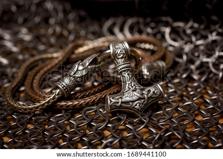 Thor's silver Hammer pendant on the chain, steel chain mail and Viking helmet. Handmade. Mjolnir. Viking's symbol. Royalty-Free Stock Photo #1689441100