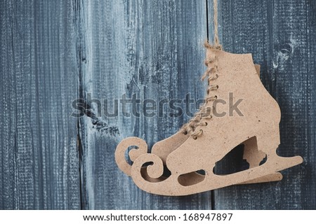 Pair of figure skates made of carton, grey wooden background
