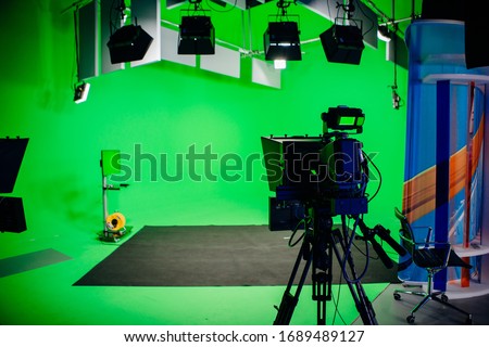 TV Studio recording show.Reportage shooting.TV NEWS program studio with video camera lens and lights.Positioned stage big professional broadcasting camera with headphones.Green key studio Royalty-Free Stock Photo #1689489127