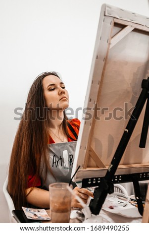 A young woman painstakingly draws her picture with brushes on easels in an art class. learning to draw , art school, creativity and the concept of people