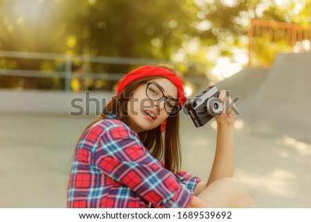 Stylish hipster girl holding retro camera in hands on a bright sunny day. Youth concept
