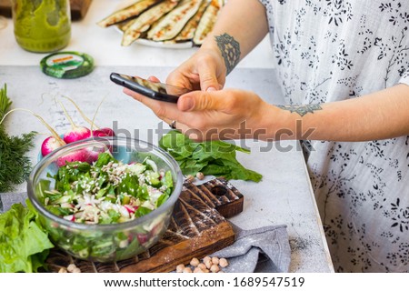 Phone picture of food. Hands make smartphone photography of summer fresh kale, cabbage salad for social media blogging. Concept for online order services. Vegan meal.