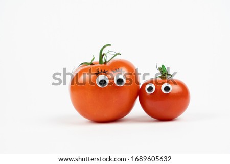 Two tomatoes with funny faces, white background and copy space