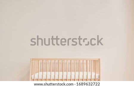 Wooden cradle and crib bed, pink wall, sun and cloud toy interior room.
