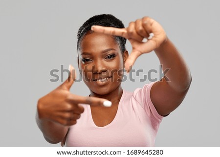 people and photography concept - happy african american woman making photo frame gesture