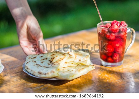Georgian Traditional dish Khachapuri in the village on sunny day with glass of iced strawberries