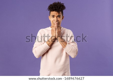 Portrait of anxious young worried hipster guy, 20s male being scared of what will happen next, scared getting sick, frowning and panicking, standing alarmed over purple background