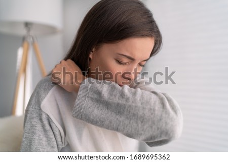 COVID-19 cover cough Coronavirus reducing of risk of spreading the infection by covering nose and mouth when coughing and sneezing with tissue or flexed elbow. Asian woman cough in arm prevention. Royalty-Free Stock Photo #1689695362