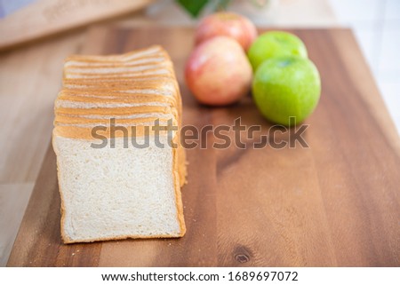 slice white bread on cutting board with apples  and banana with bowl of fresh green salad in kitchen, healthy food concept.