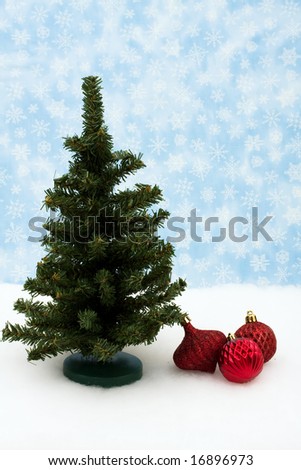 Red glass Christmas balls and tree on snow with snowflake background, Christmas balls