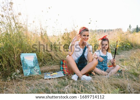 Sunny nature, mom and daughter paint a picture in a park , painting a Little Child, Child Creativity. Mother's Day