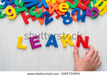 Child playing with magnetic letters and numbers. Spelling the word LEARN.
