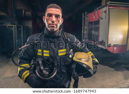 Portrait of a fireman wearing firefighter turnouts holding helmet ready for emergency service.