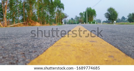 The surface of the paved road has a dividing line for traffic lanes.