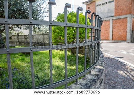 View of metal vintage fence with thin curved frames with blur garden background