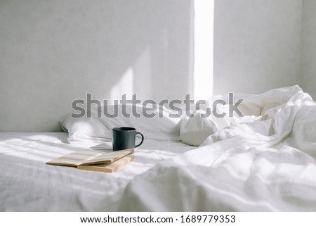 Light cozy bedroom, Coffee or tea cup and an open book on the bed. Royalty-Free Stock Photo #1689779353