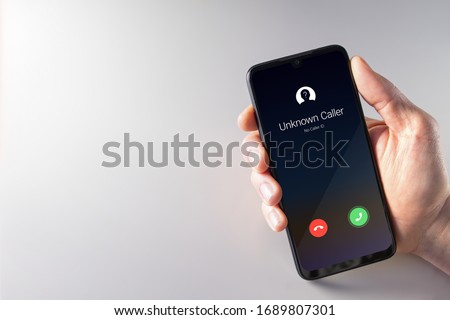 Male hand holding a smartphone with unknown caller displayed on screen. Privacy, fraud, cybercrime and spying concepts Royalty-Free Stock Photo #1689807301