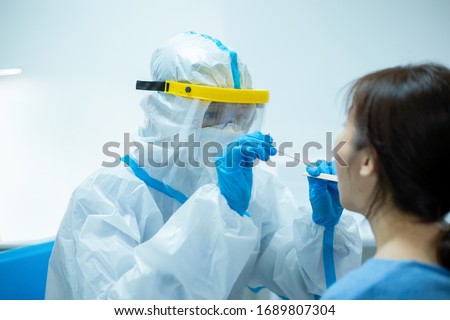 Coronavirus test - Medical worker taking a throat swab for coronavirus sample from a potentially infected woman with the isolation gown or protective suits and surgical face masks Royalty-Free Stock Photo #1689807304