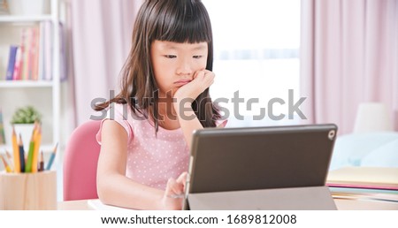 Asian girl student feel boring while using tablet pc to have online class happily at home