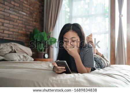 peer pressure. young teenage asian girl shocked while using her mobile Royalty-Free Stock Photo #1689834838