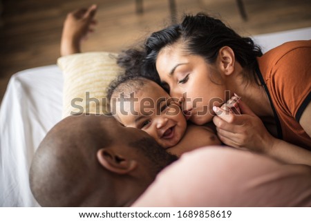 Happy parenting. African American parents with daughter on bed. Royalty-Free Stock Photo #1689858619