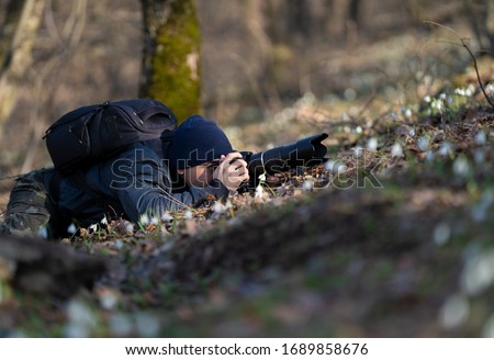 Professional photographer taking picture in nature with a digital camera and telephoto lens