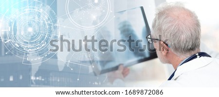 Senior doctor looking at x-ray in clinic; panoramic banner