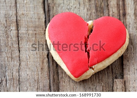 Cracked heart shaped cookie decorated with red icing as a concept of broken heart, breakup and end of relationship Royalty-Free Stock Photo #168991730