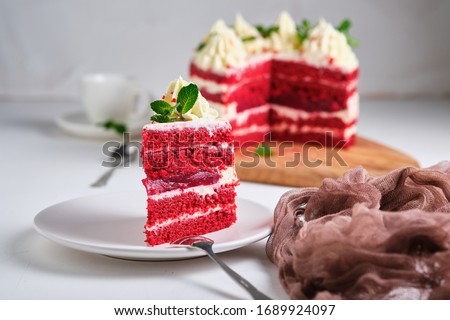 Cake red velvet. Dessert garnished with cream cheese cream and mint leaves. Red cake with a raspberry layer in the middle.