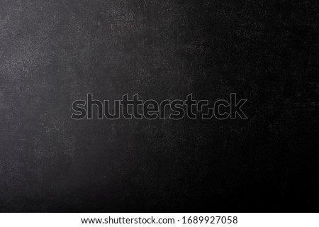 Black gray painted concrete texture or background with shadow and grain elements. High contrast and resolution image with place for text. Template for design