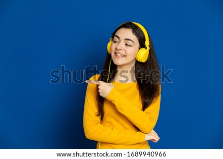 Brunette young girl wearing yellow jersey on a blue background