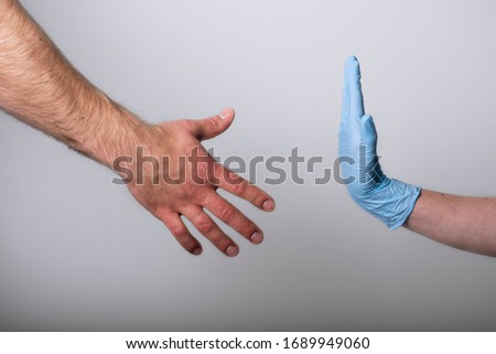 Hand in medical glove refuses to shake hand without medical gloves. Healthcare and hygiene concept Royalty-Free Stock Photo #1689949060